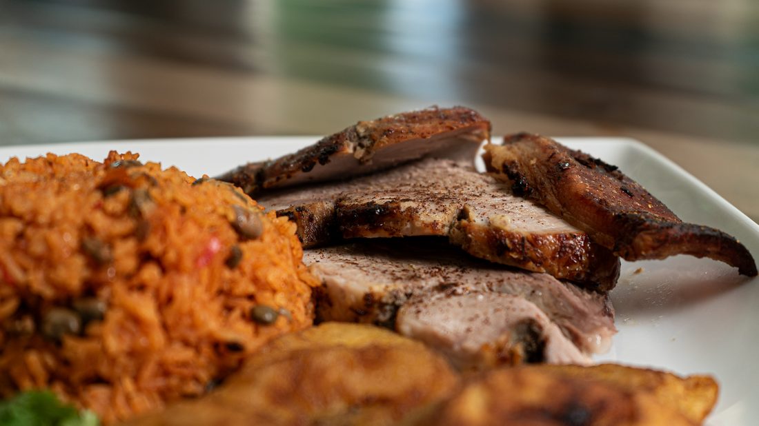 Arroz con gandules (rice with pigeon peas) served with sliced pernil